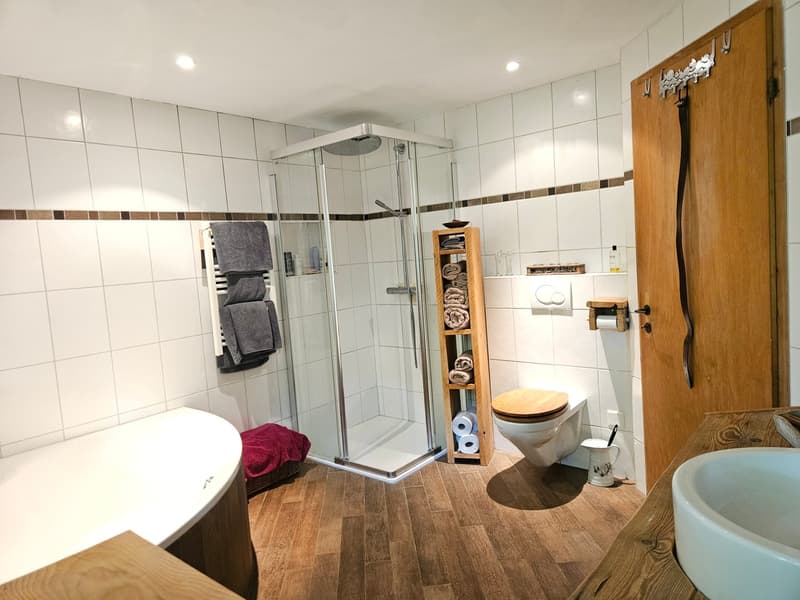 white tiles, wooden floor, bathtub, shower, toilet, wooden shelf, towels, sink