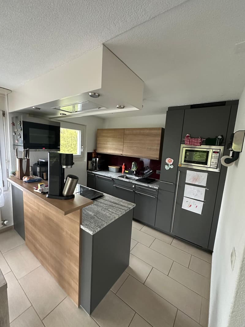 modern kitchen with island, granite countertops, wooden cabinets, stainless steel appliances, microwave, refrigerator, coffee machine, sink, faucet, window