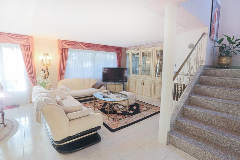 white couches, coffee table, TV, cabinet, carpet, staircase