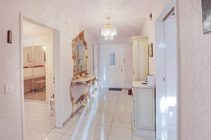 tiled floor, pink walls, gold mirror, white cabinet, chandelier