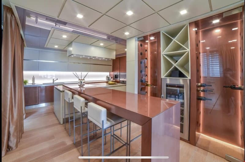 Spacious modern kitchen with wooden cabinets, granite countertops, built-in appliances, wine rack, and bar seating area.