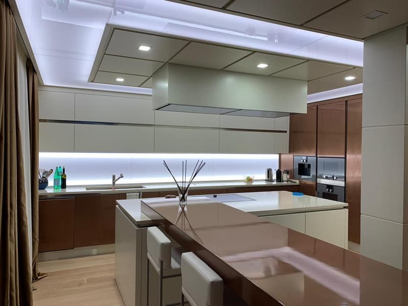 Modern kitchen with sleek gray cabinets, built-in appliances including a dishwasher, and a large central island with a white countertop