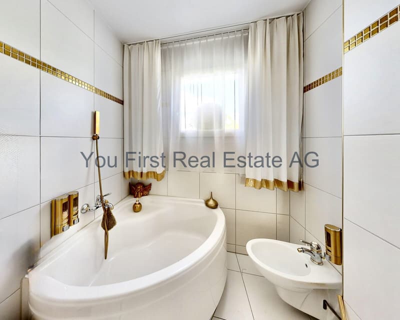 Wellness-Oase mit Eckbadewanne: Lichtdurchflutetes Badezimmer mit elegantem Goldakzent