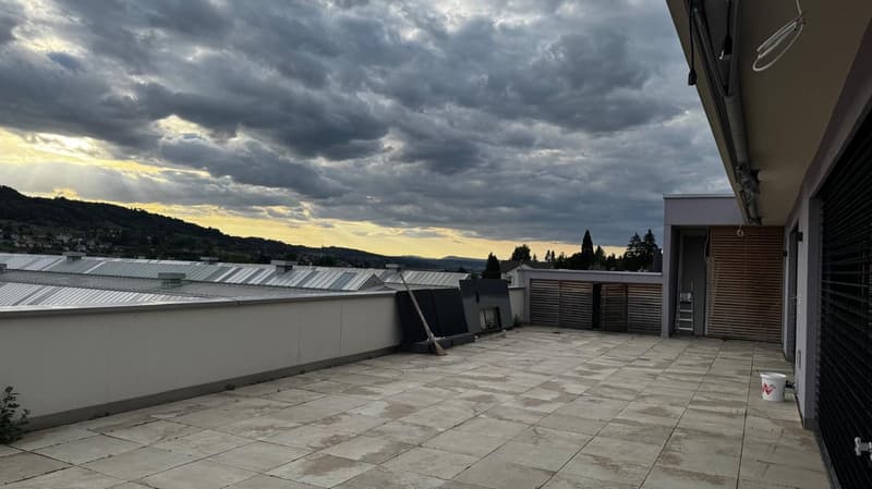 tiled rooftop terrace with surrounding walls, open view to city and mountains, broom, bucket