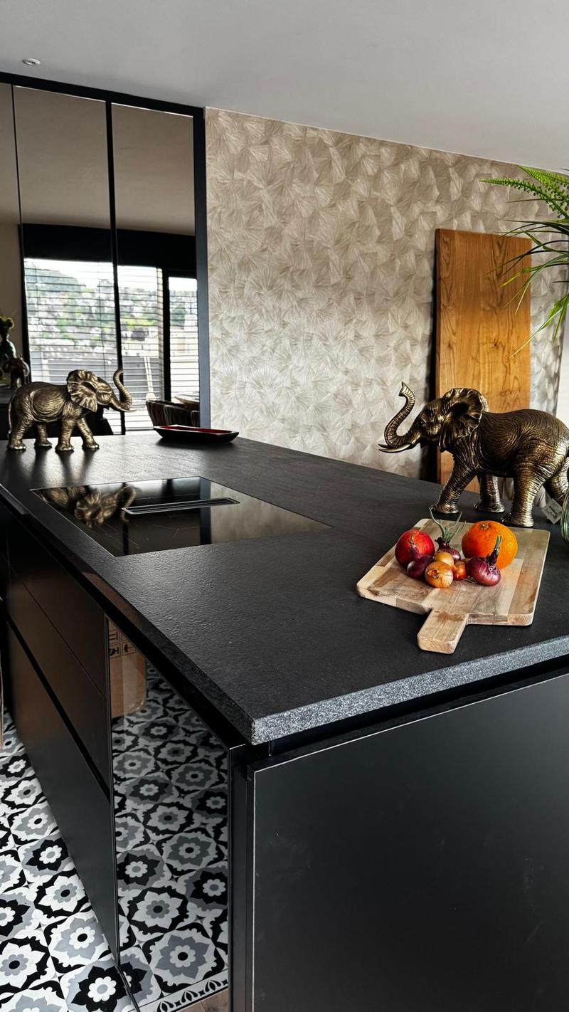 black countertops, black cabinets, decorative elephant statues, fruit on cutting board, patterned flooring, windows