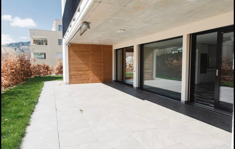 modern building with wooden door, glass windows, tiled floor, garden