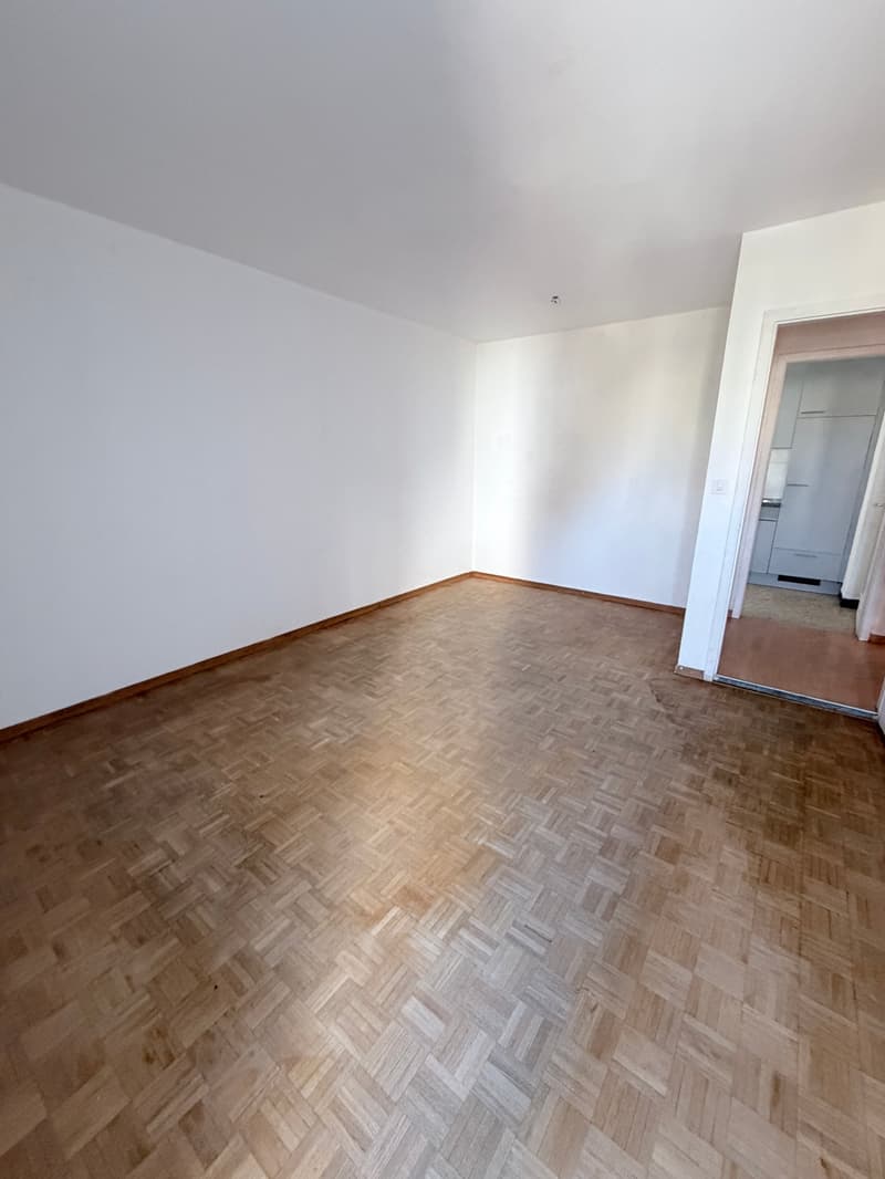 empty room, wooden parquet floor, white walls, open door to another room