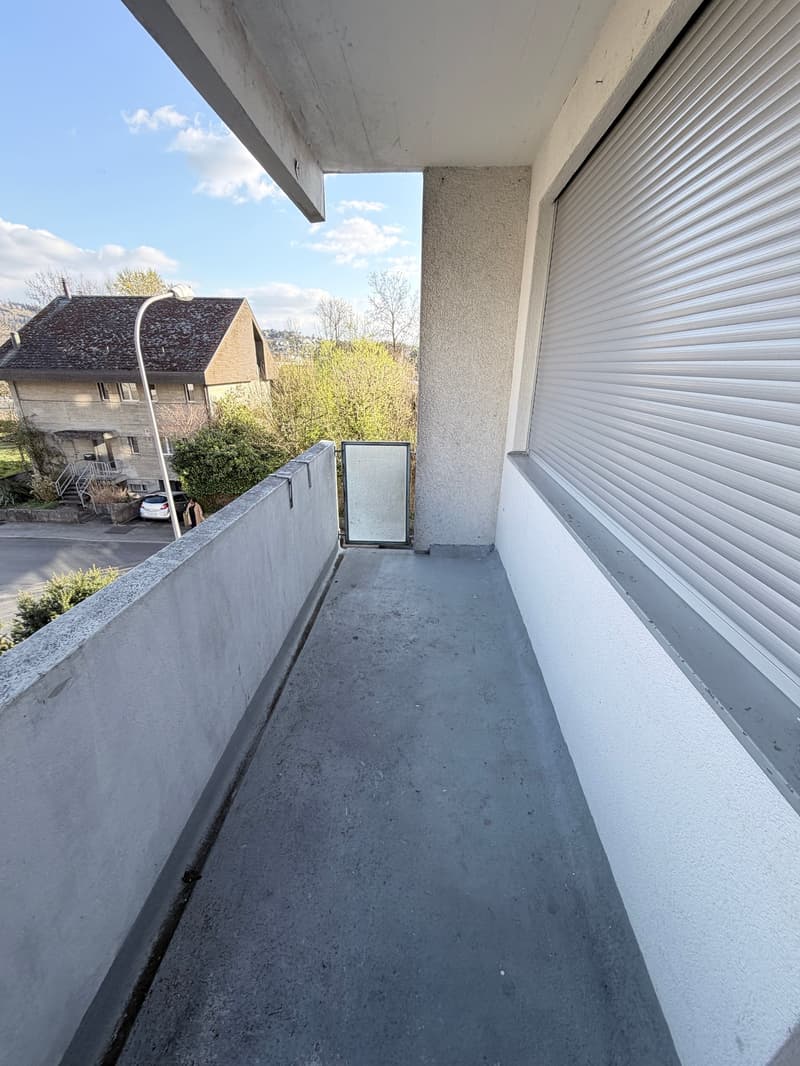 Empty balcony with concrete floor, concrete wall, and metal shutters