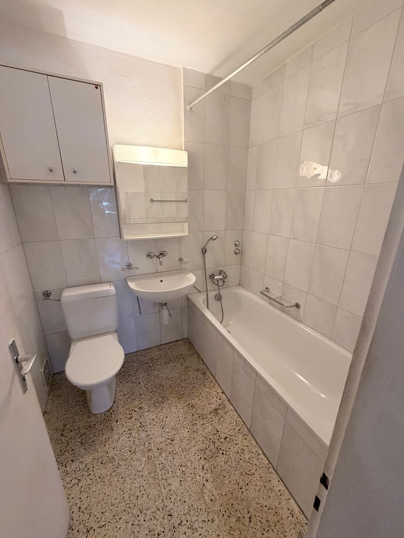 Bathroom with white tiles, white bathtub, white sink, white toilet, white cabinets, white shower curtain