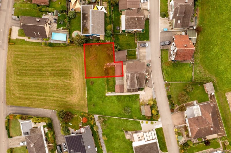 Top down view of neighborhood, houses, driveways, yards, swimming pool, large open field