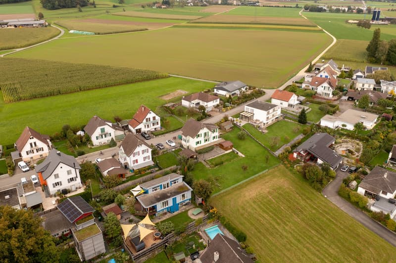 Neighborhood with houses surrounded by green fields and a swimming pool.