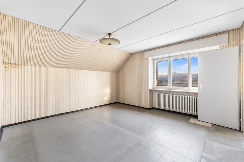 empty room, ceiling light, wall-mounted radiator, wooden wall paneling, gray floor, an open door