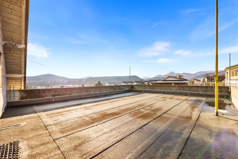 Roof with concrete surface, concrete railing, unobstructed view of mountains and buildings