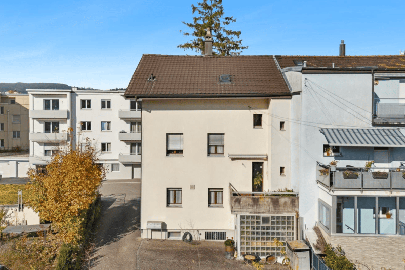 white apartment building, balconies, brown roof, multiple windows, chimneys