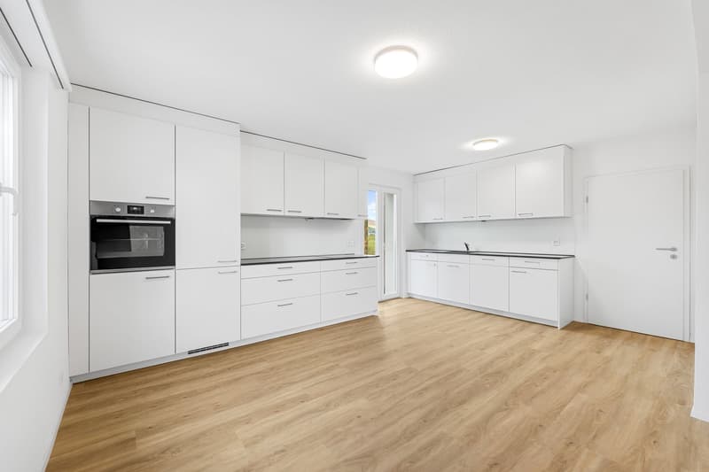 modern kitchen with white cabinets, wooden floor, built-in oven, sink, and faucet