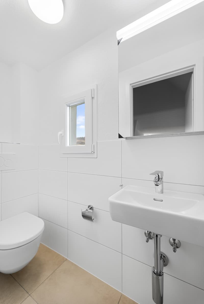 Bathroom with white tiles, white toilet, white sink, silver faucet, small window, mirror