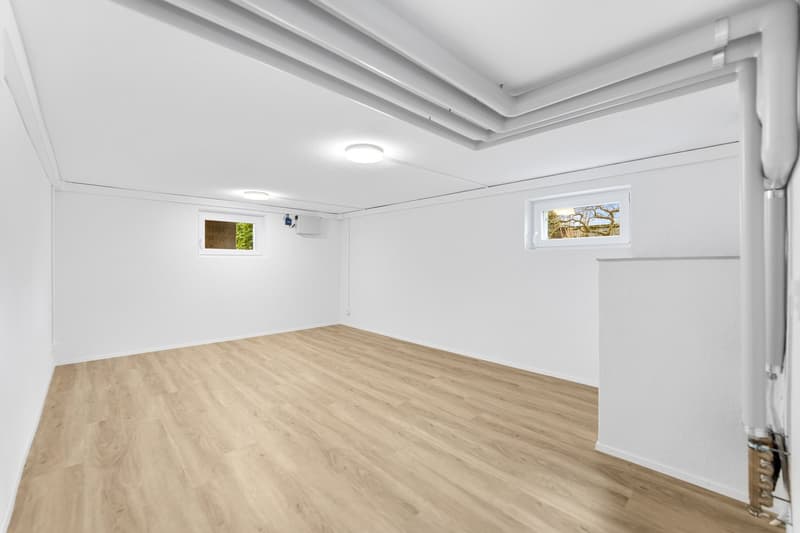 empty room, white walls, wooden floor, two small windows, ceiling lights