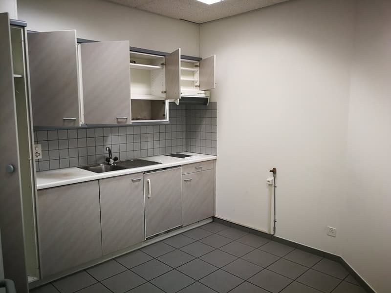 Fully equipped kitchen with grey cabinets, tiled backsplash, sink, and appliances including a washing machine and dishwasher
