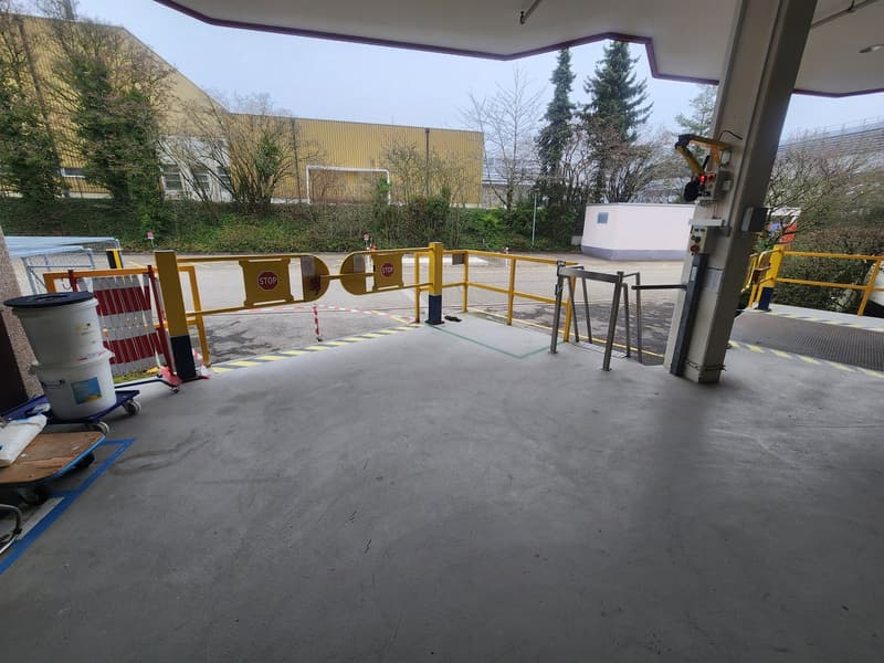 empty parking lot, yellow barriers, stop signs, trash bins, wheelbarrows, metal railings, control panels