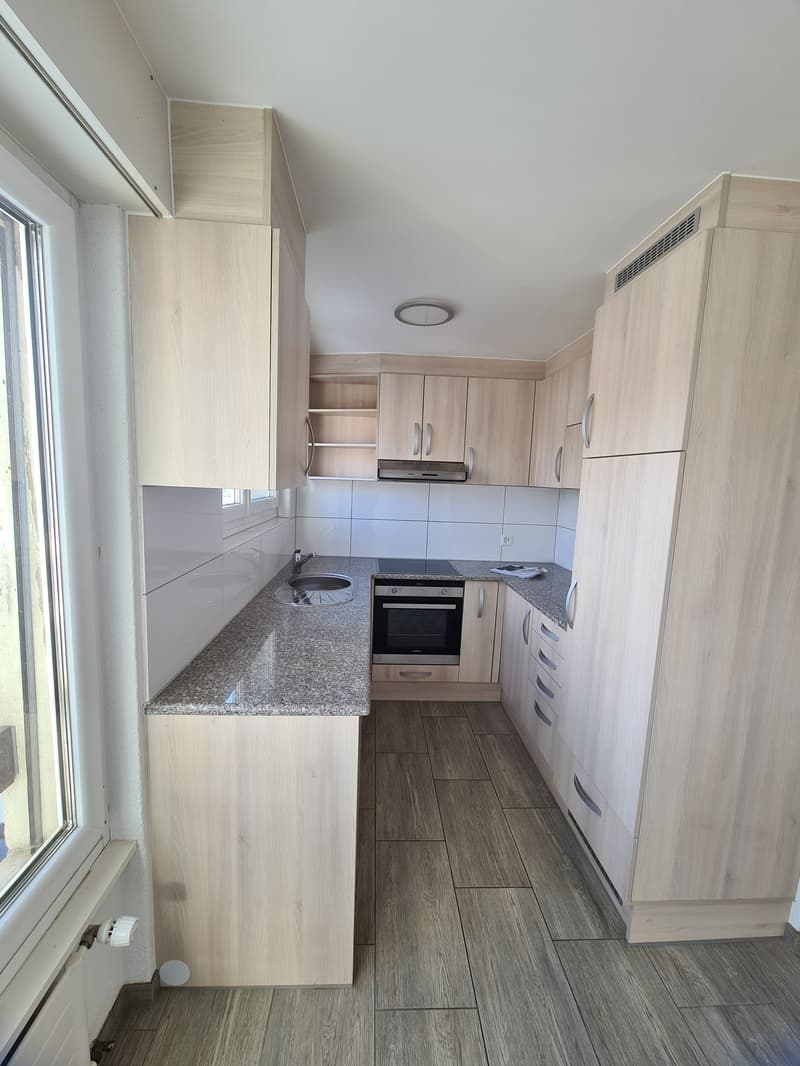 modern kitchen with wooden cabinets, granite countertop, built-in oven and stove, sink with faucet, and a window