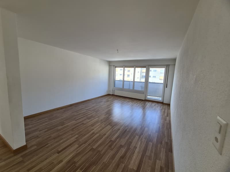 empty room, wooden floor, white walls, sliding glass door to balcony, large window