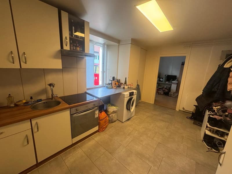 White kitchen cabinets, stainless steel sink, induction cooktop, dishwasher, washing machine, wooden counter, tiled floor, white tiles on the wall, fluorescent ceiling light
