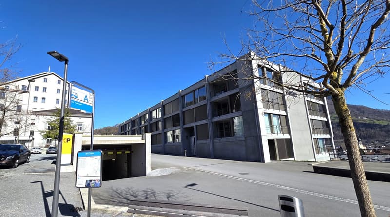Modern apartment building with underground parking, multiple floors, large windows, and a flat roof.