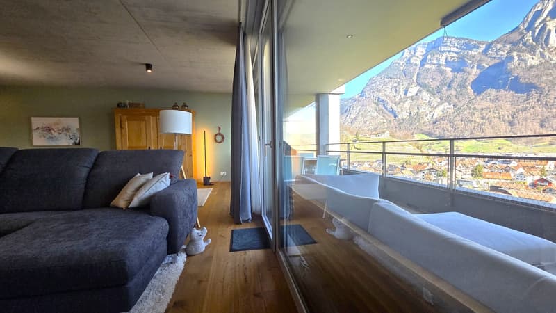 large windows, balcony, couch, rug, wooden floor, lamp, wooden cabinet, painting