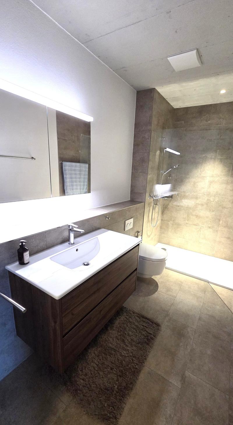 modern bathroom with white sink, wooden cabinet, white toilet, glass shower, towel rack