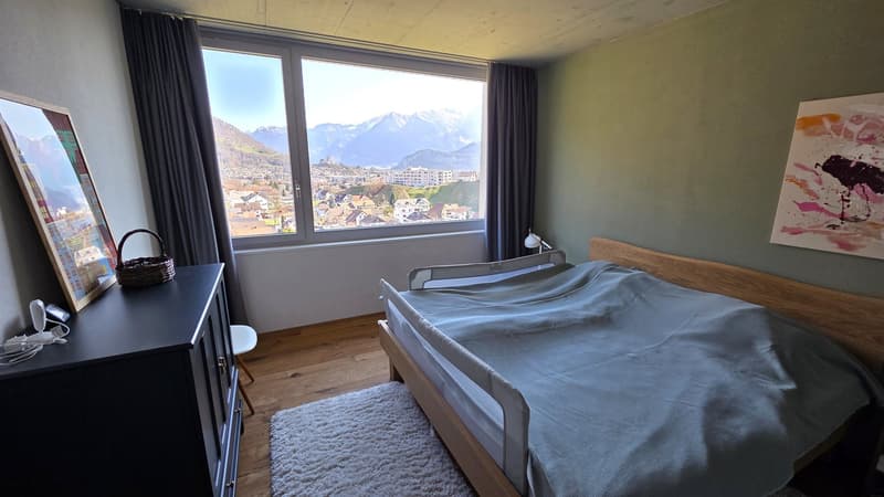 bedroom with bed, window, wooden floor, cabinet, basket, painting, rug, lamp