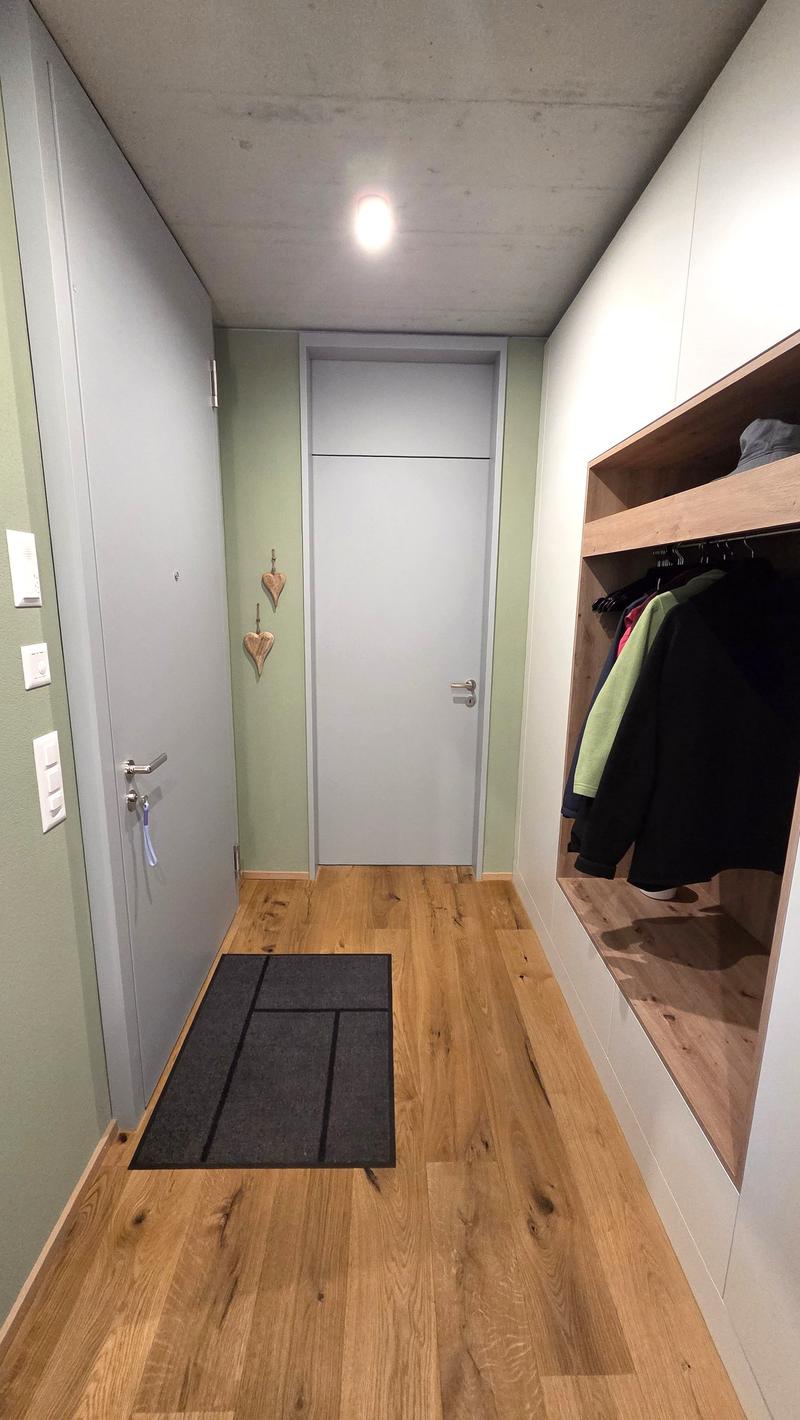 wooden floor, white walls, white doors, black rug, closet with clothes