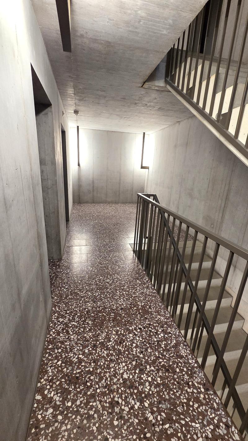 Concrete walls, marble floor, metal railings, stairs, small windows