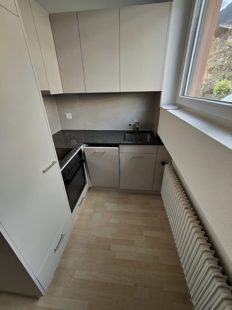 modern kitchen with white cabinets, granite countertop, stainless steel sink, built-in oven, window with view