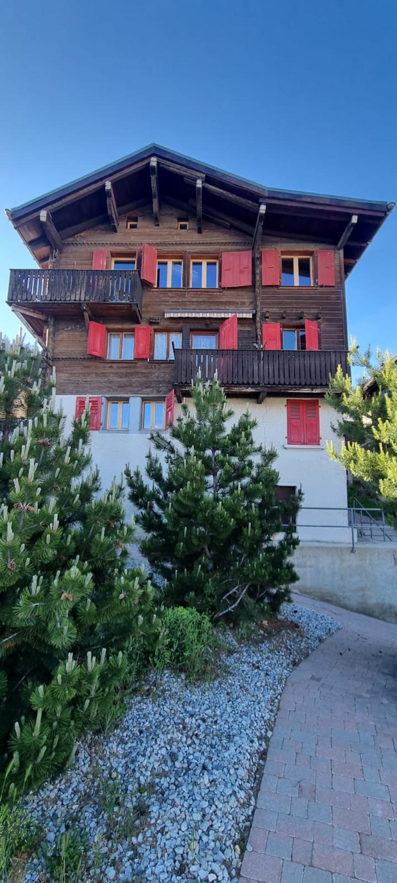 2 story chalet, red shutters, multiple balconies, wooden exterior, white interior, brick path