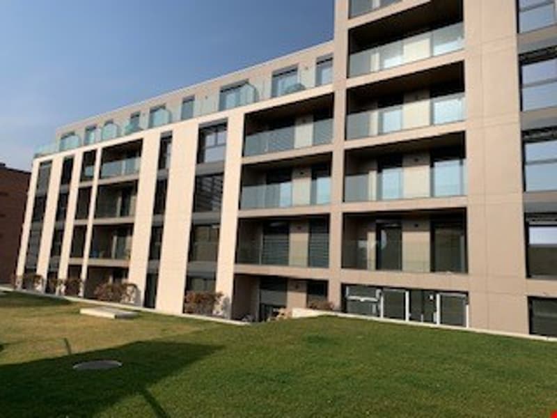 modern apartment building, multiple floors, large windows, balconies, green lawn