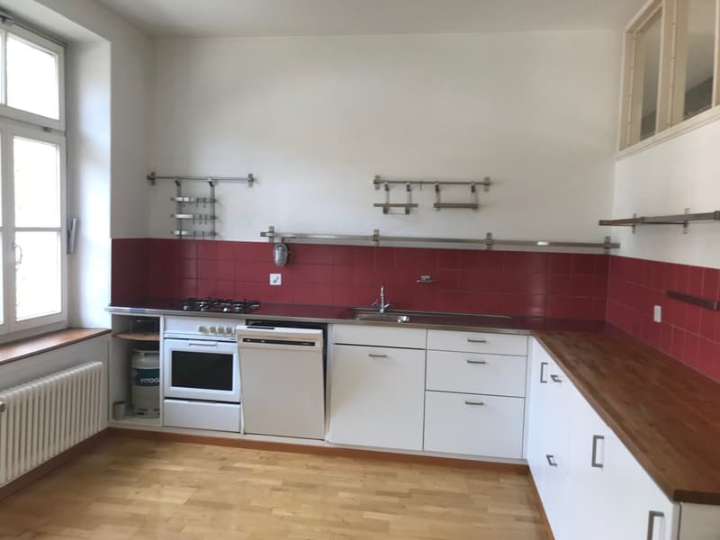 modern kitchen with white cabinets, red tiles, wooden floor, gas stove, dishwasher, sink, window
