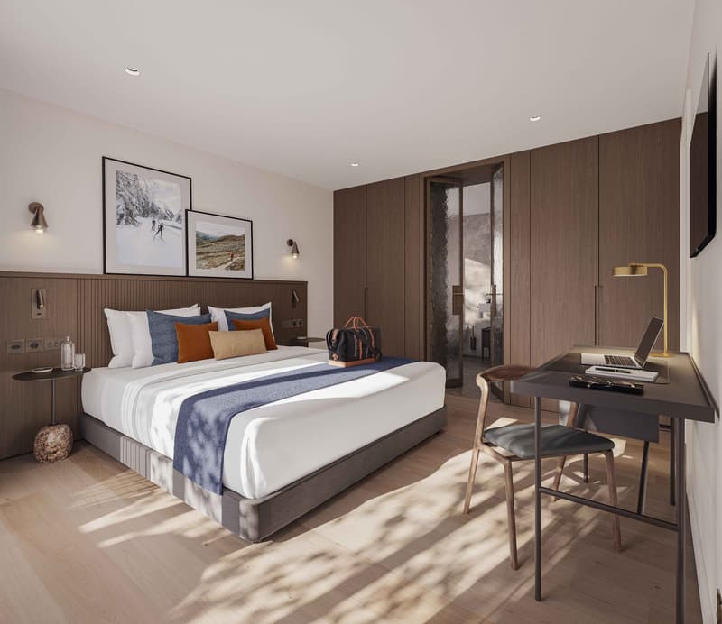 Spacious bedroom with a large bed, wooden furniture, and artwork on the walls. The room has a desk and chair for a workspace, and a balcony or terrace is visible through the window.