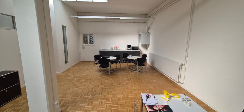 empty room, wooden floor, white walls, kitchen area with sink, microwave, coffee machine, cabinets, tables and chairs, radiator