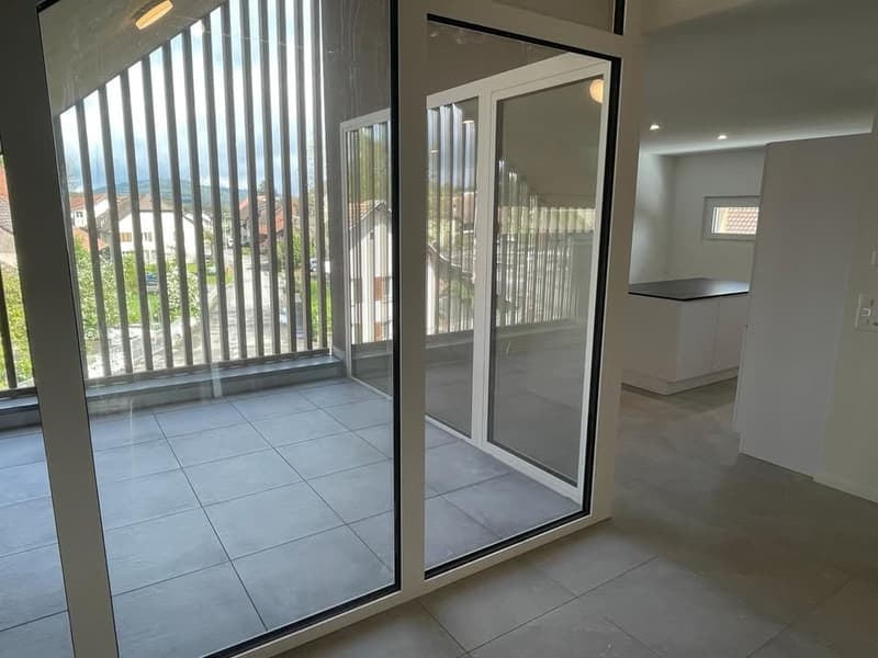 Empty balcony with sliding glass doors, wooden railing, tiled floor, city view from balcony