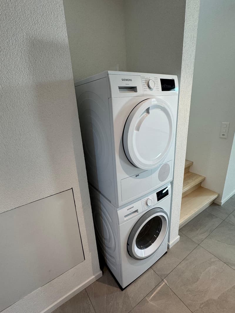 white laundry machines, tile flooring, stairs leading up to another level
