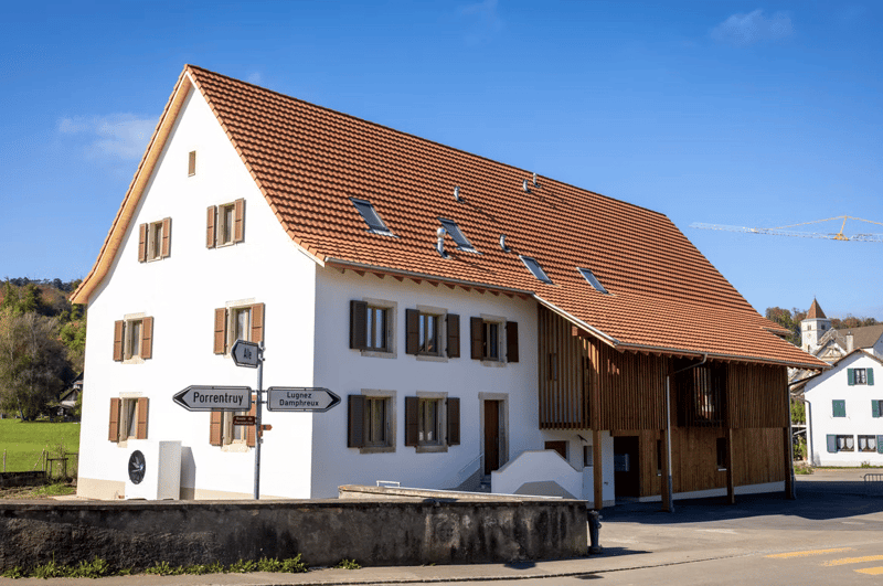 2 story house, red roof, white walls, brown shutters, large window, wooden wall