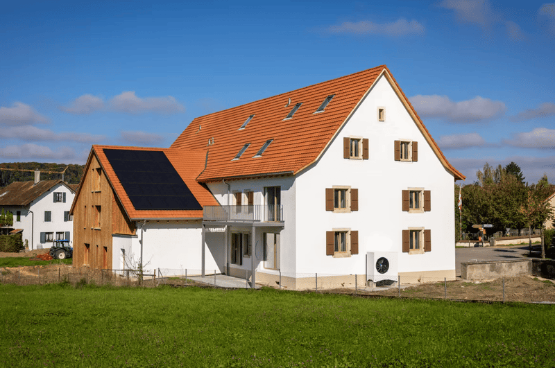 2 story house, white exterior, brown roof, windows with shutters, solar panels, balcony, outdoor air conditioner