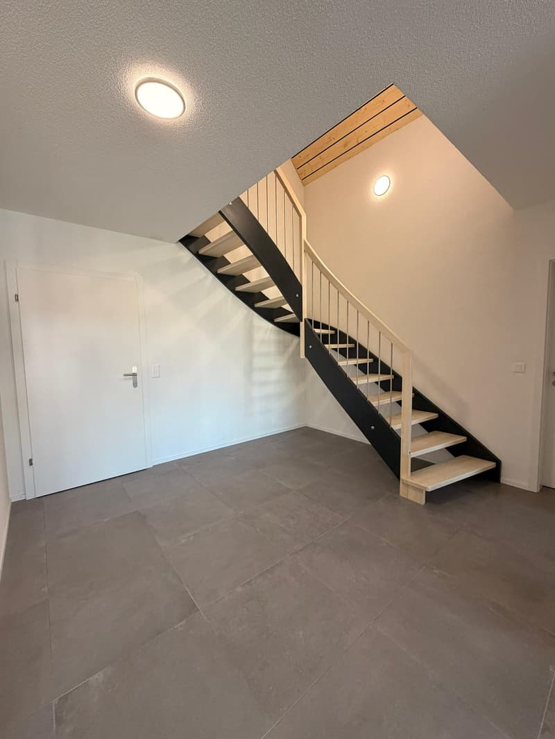 Open hallway, wooden stairs, wooden railing, white doors, gray tiled floor
