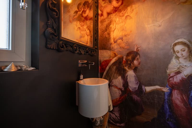 Bathroom with a white sink, black walls, a large painting, and a window.