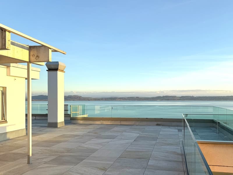 Large outdoor space with tiled floor, glass railing, overlooking sea