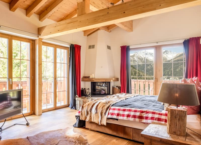 Das Masterschlafzimmer mit eigenem Kamin bietet im Obergeschoss ein einzigartiges Raumgefühl - geprägt von grossen Fensterfronten, hohen Decken und einer atemberaubenden Aussicht.
