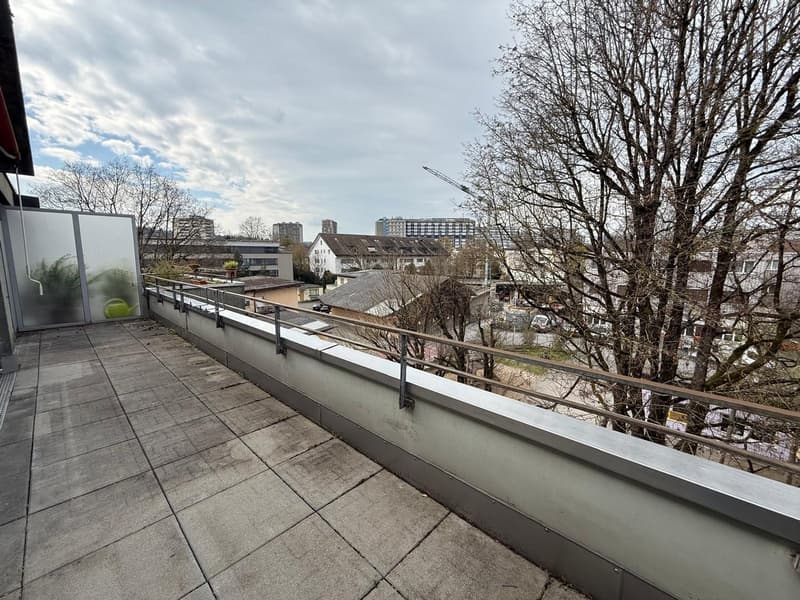Balcony with tiled floor, metal railing, glass wall, and a view of the city