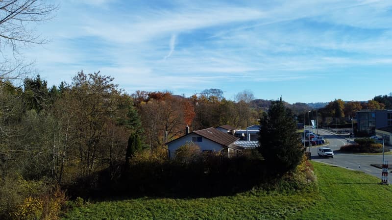 Detached house with brown roof, located in the middle of a forest with a clear view on the hills in the distance