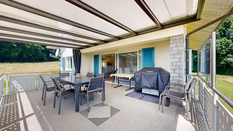Outdoor living area with a dining table, chairs, and an awning, a view of the outside landscape