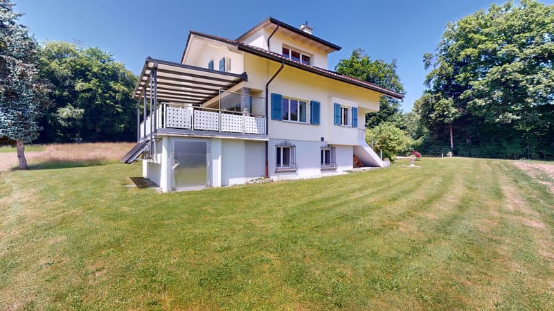2 story house, yellow exterior, balcony, white windows, tiled roof, garage door, trees, wide lawn